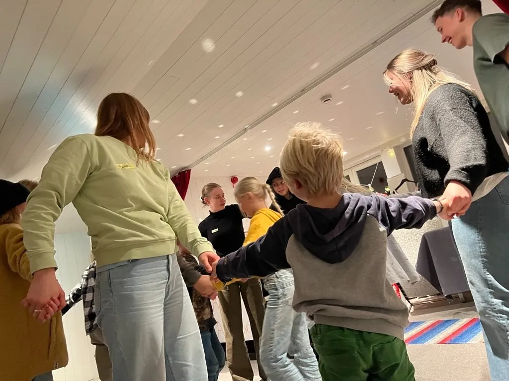 Barn och unga hand i hand i en ringdans